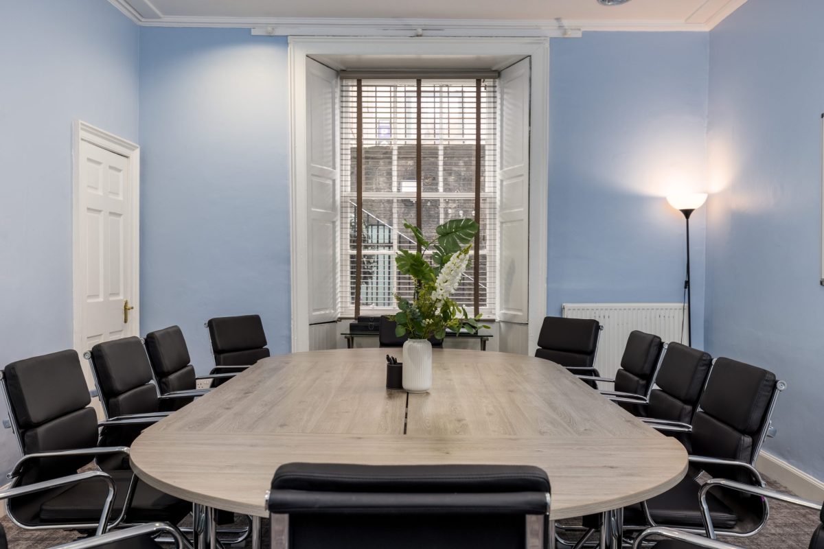 Boardroom at 28 York Place with a large wooden table, black leather chairs, and a tall sash window.