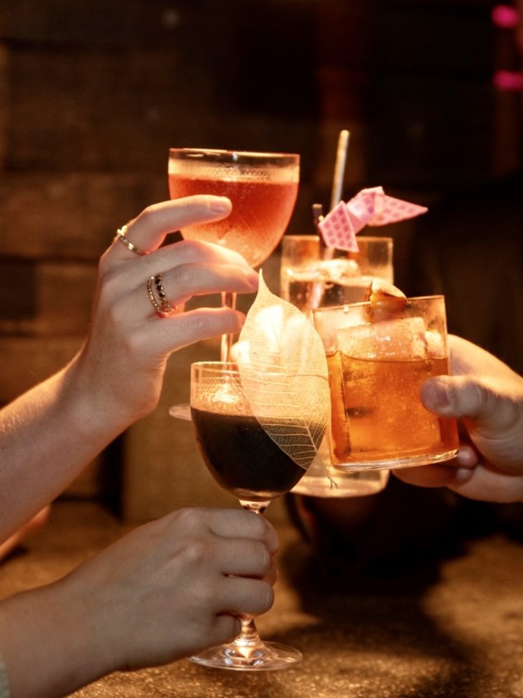 Three cocktails being clinked together in celebration in Nightcap cocktail bar