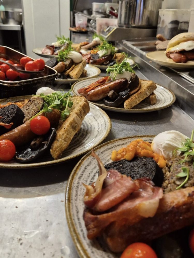 Full Scottish breakfasts being plated in the kitchen at Edinburgh Larder in Edinburgh