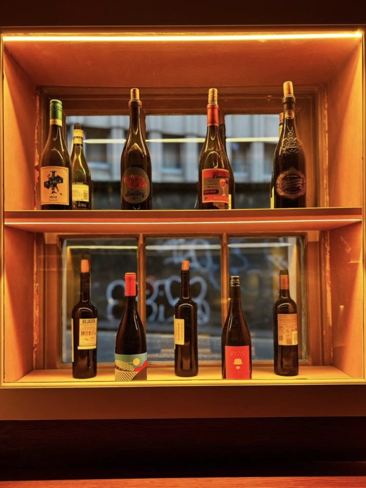 Wine bottles lined up in an aesthetic row in Folly Spirits Lab, lit up by a warm golden glow