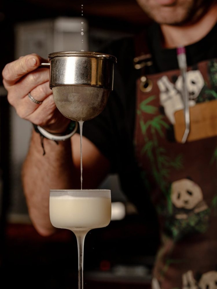 Panda and Sons bartender creating a fancy ice-cold cocktail with a sieve
