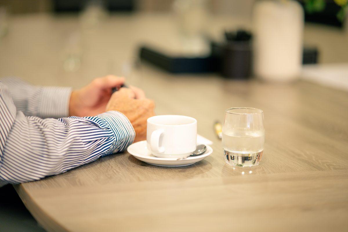 Person enjoying a biscuit, coffee, and glass of water at a meeting table at 28 York Place.